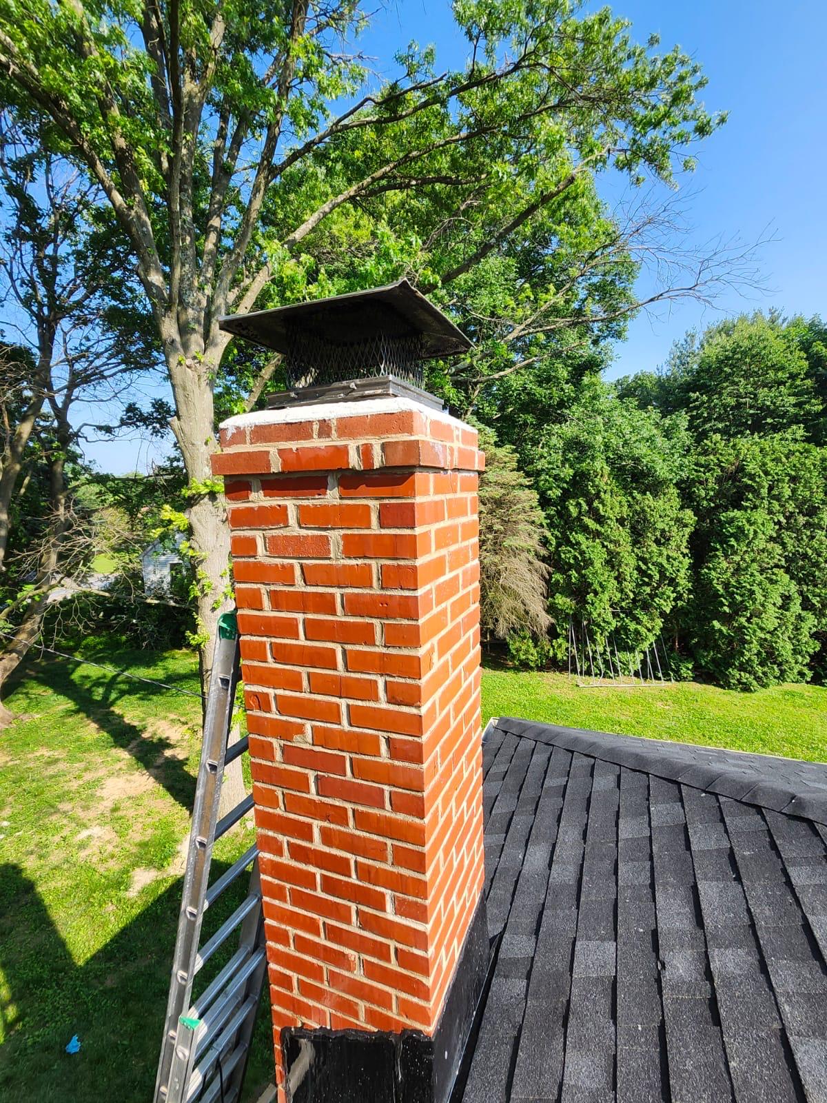 Tall brick chimney with white cap on roof